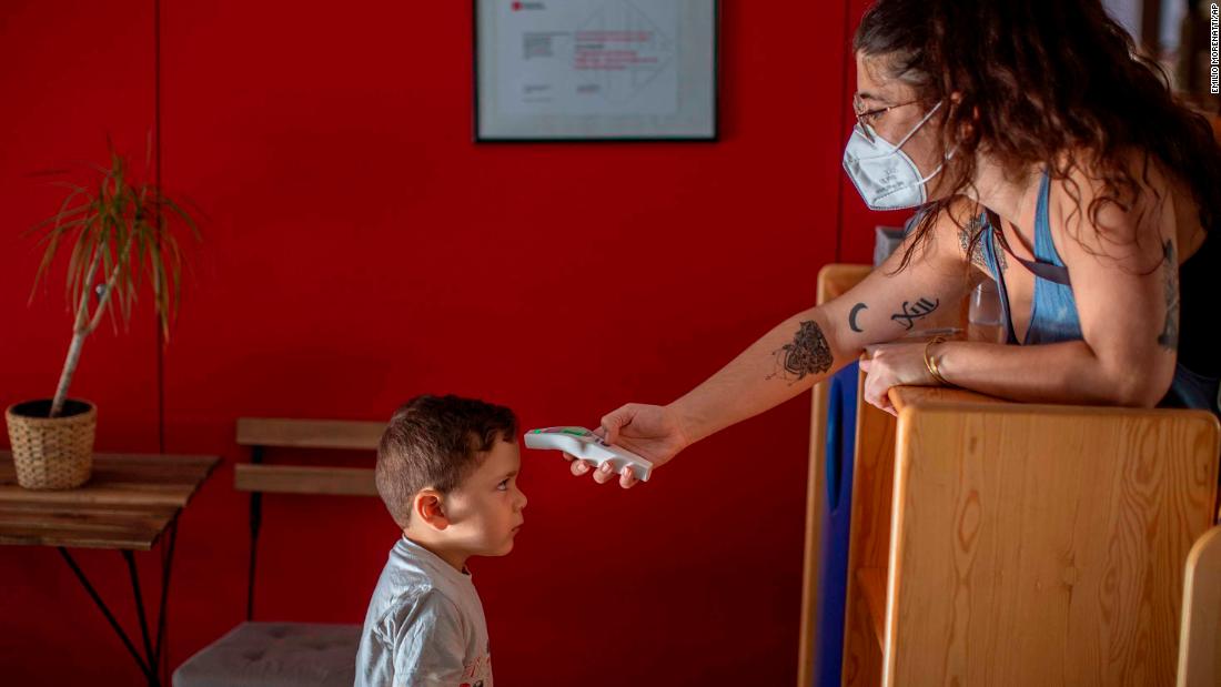 Hugo, 3, has his temperature taken by a teacher as he arrives at kindergarten in Barcelona on June 26.